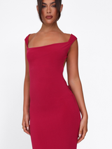 A woman wears the TIGERMIST ZITA DRESS in Salsa Deep Red, showcasing a fitted bodycon silhouette with a sleeveless, square neckline design, standing against a plain white background.