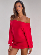 A woman wearing the TIGERMIST JANINE MINI DRESS in red stands against a light gray background, confidently facing the camera with one hand by her side.
