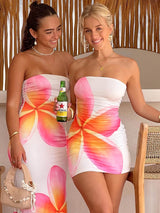 Two girls smiling together and are both wearing the same tropical floral dress. One girl is wearing a maxi and the other is wearing a mini dress.