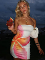 Girl wearing a white strapless mini dress and is holding a red alcoholic beverage, and white shoulder bag.